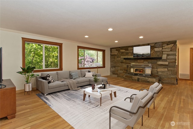 living room with a wood stove, ornamental molding, and light hardwood / wood-style flooring