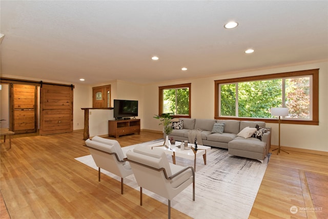 living room featuring a barn door, light wood-type flooring, and crown molding