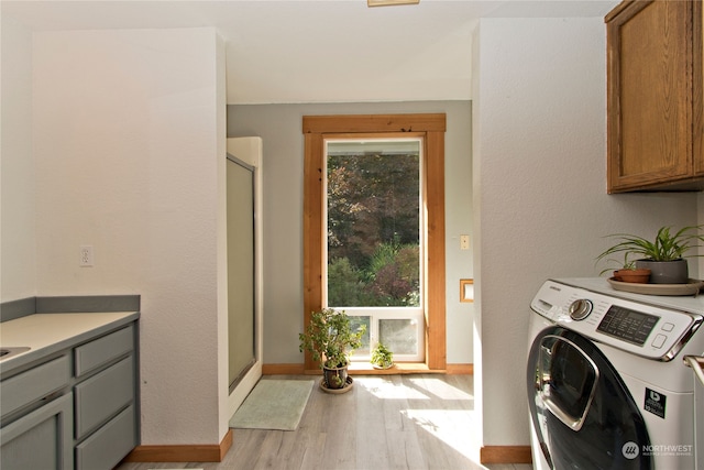 laundry area with cabinets, light hardwood / wood-style floors, and washer / dryer