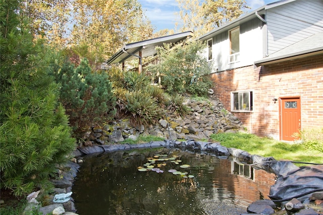 view of side of home with a small pond