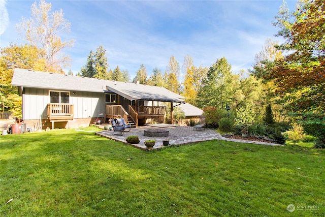 back of property with a fire pit, a yard, a patio, and a wooden deck