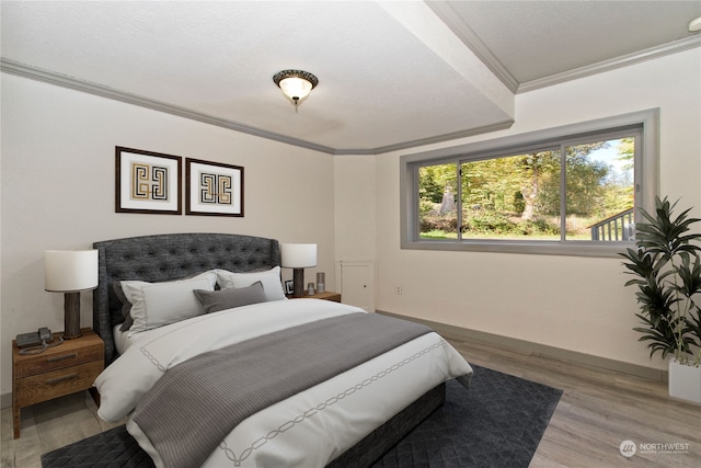 bedroom featuring wood-type flooring, a textured ceiling, and crown molding