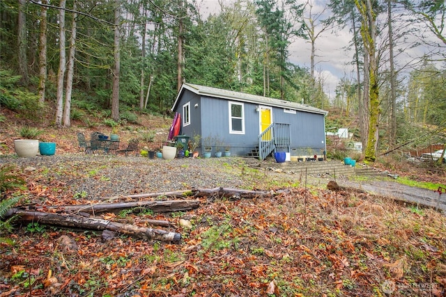 view of front of house with crawl space, entry steps, and a forest view