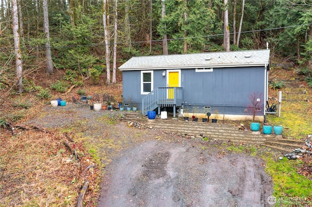 view of front of property featuring crawl space, a forest view, and roof with shingles