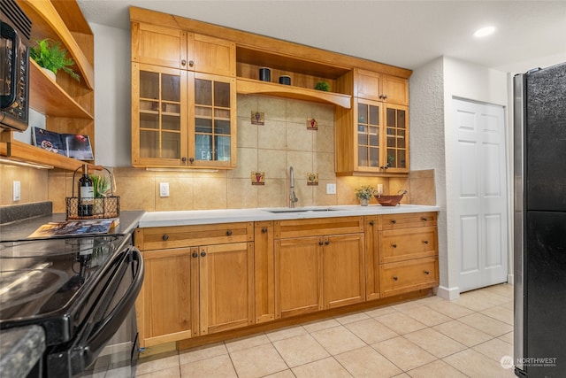 kitchen with light tile patterned flooring, sink, tasteful backsplash, and black appliances