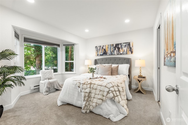 bedroom featuring light colored carpet and a baseboard heating unit