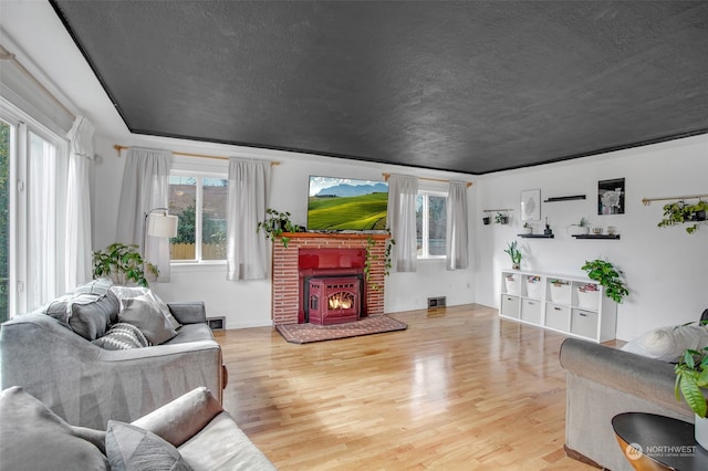 living room featuring a brick fireplace, a textured ceiling, and hardwood / wood-style floors