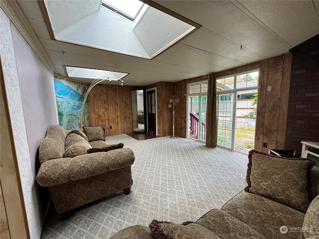 carpeted living room featuring a skylight, wooden walls, a fireplace, and a textured ceiling