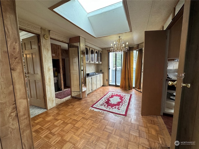 kitchen with a textured ceiling, light parquet flooring, a chandelier, and vaulted ceiling with skylight