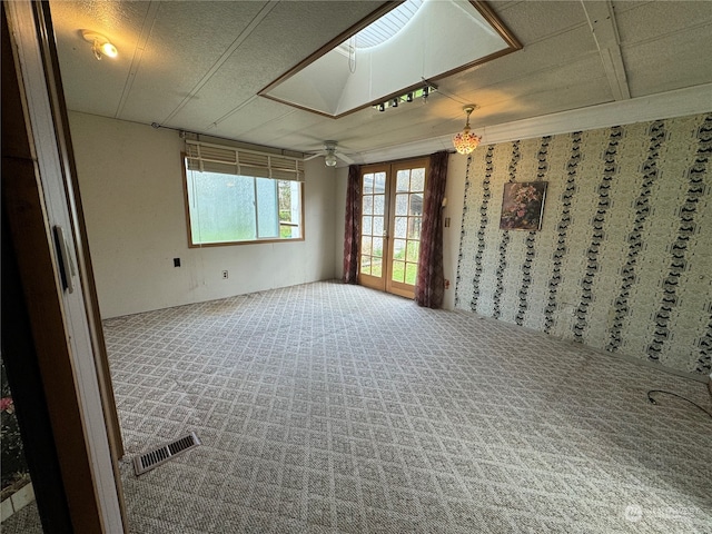 spare room with carpet floors, french doors, a skylight, and ceiling fan