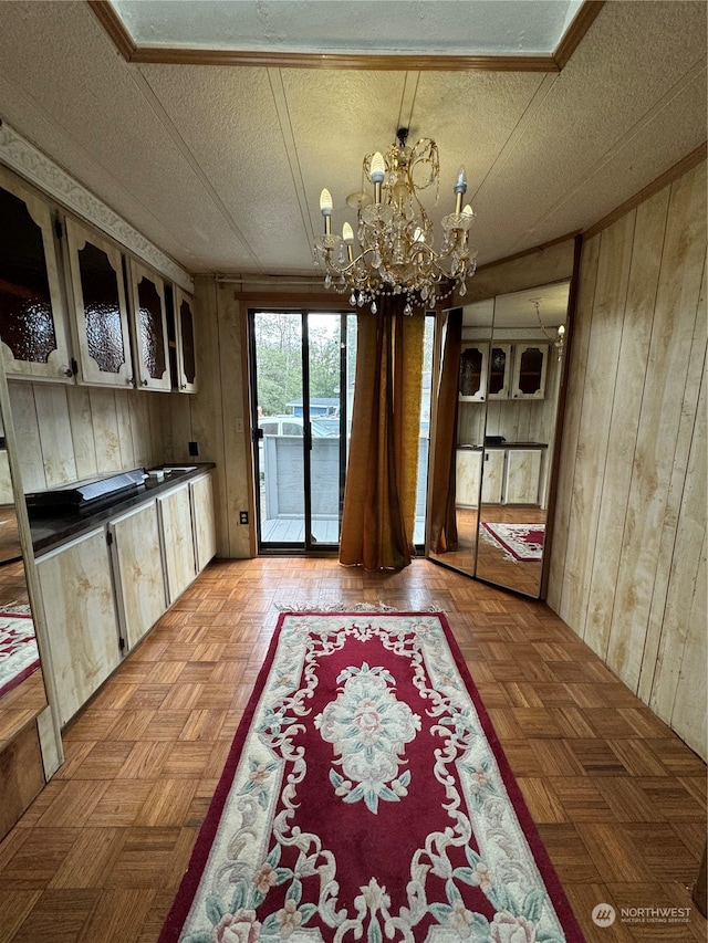 dining area featuring a notable chandelier, wooden walls, and light parquet flooring