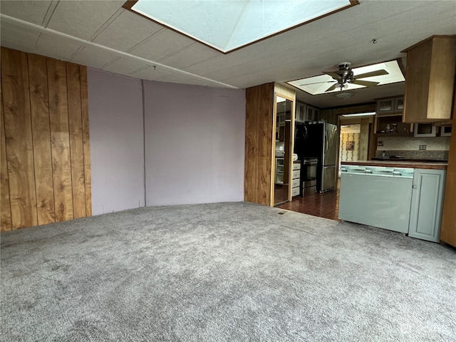 kitchen featuring ceiling fan, wooden walls, stainless steel fridge, and dark carpet