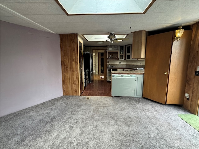 kitchen with dark carpet, stainless steel refrigerator, wood walls, and ceiling fan