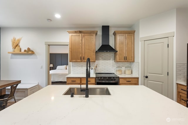 kitchen featuring wall chimney range hood, tasteful backsplash, sink, and black range oven