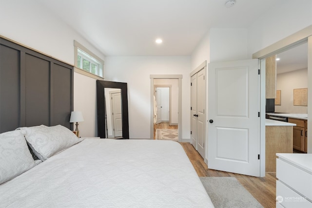 bedroom with connected bathroom and light wood-type flooring