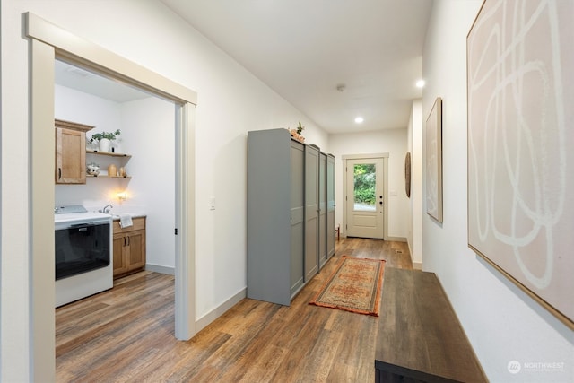 hall with washer / clothes dryer, sink, and dark hardwood / wood-style flooring