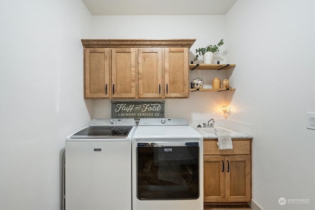 clothes washing area with sink, washer and clothes dryer, and cabinets