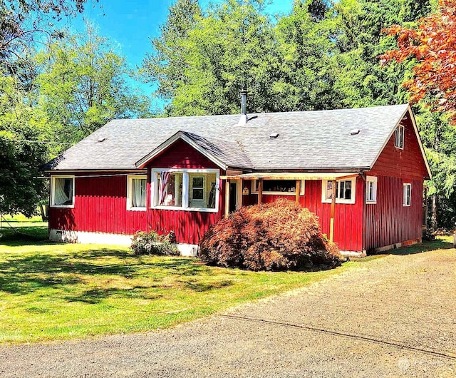ranch-style home featuring a front lawn and a shingled roof