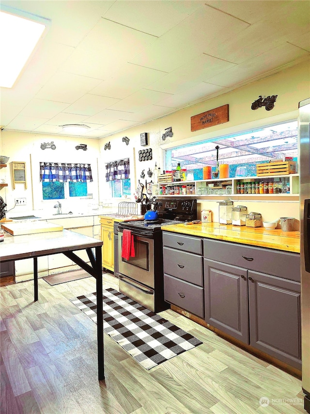 kitchen with stainless steel range with electric stovetop, gray cabinets, and light hardwood / wood-style floors