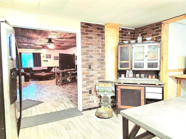 kitchen with wood-type flooring, brick wall, and ceiling fan