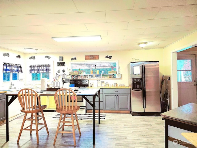 kitchen featuring stainless steel refrigerator with ice dispenser, light wood-type flooring, and gray cabinets