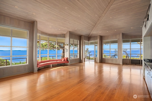 unfurnished sunroom featuring lofted ceiling, wooden ceiling, and a water view