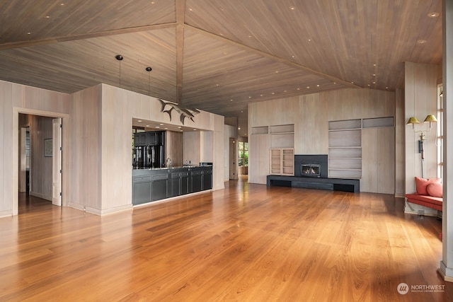 unfurnished living room with wood ceiling, light wood-type flooring, sink, and high vaulted ceiling