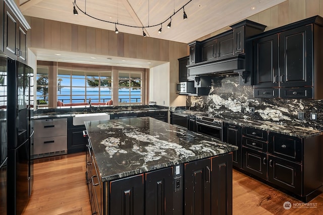 kitchen featuring dark stone counters, sink, a center island, and light hardwood / wood-style floors