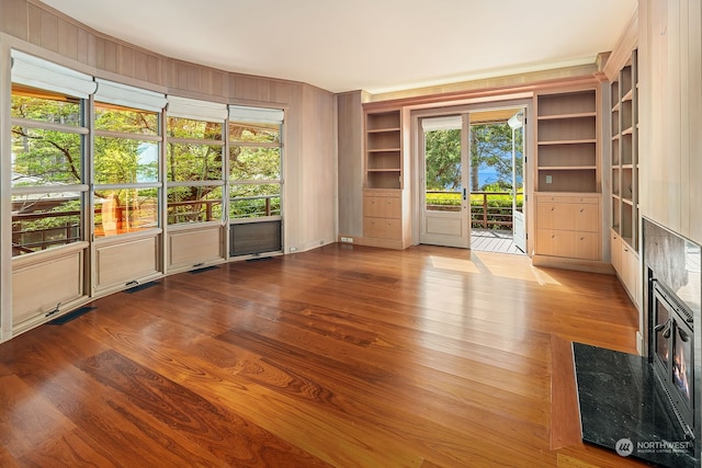 unfurnished room with built in shelves and light hardwood / wood-style flooring