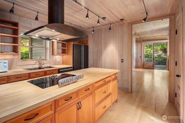 kitchen featuring light wood-type flooring, sink, butcher block countertops, island exhaust hood, and black electric stovetop