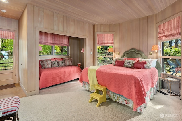 bedroom with carpet floors, wooden ceiling, and wooden walls