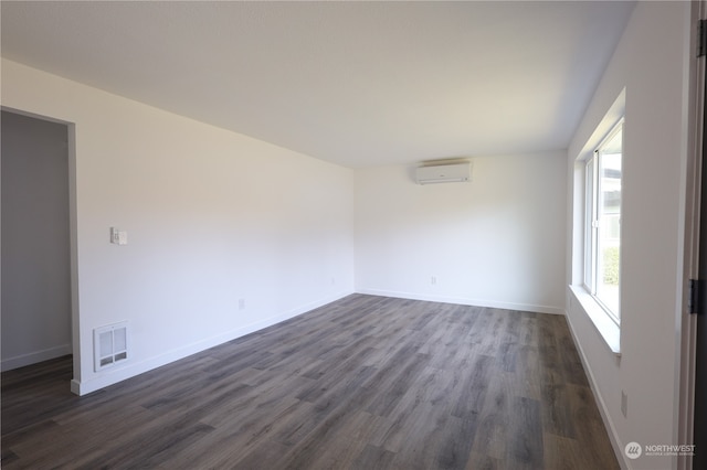 empty room featuring a wall mounted air conditioner and dark hardwood / wood-style floors