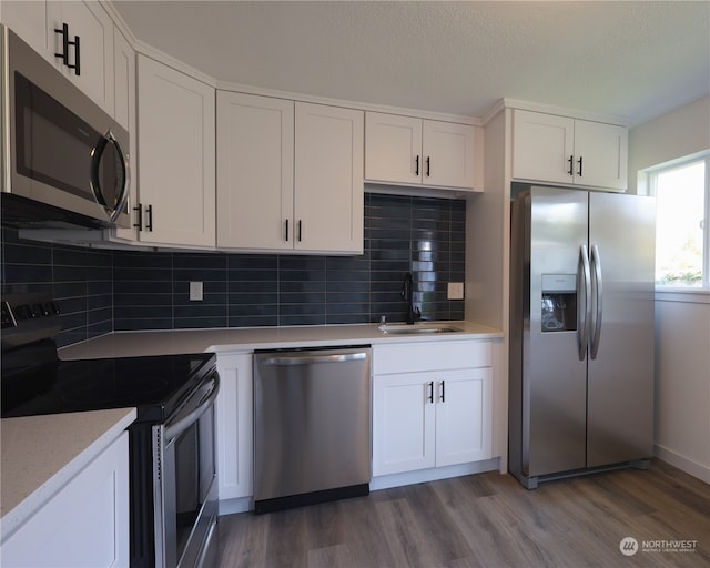 kitchen featuring stainless steel appliances, wood-type flooring, sink, and white cabinetry