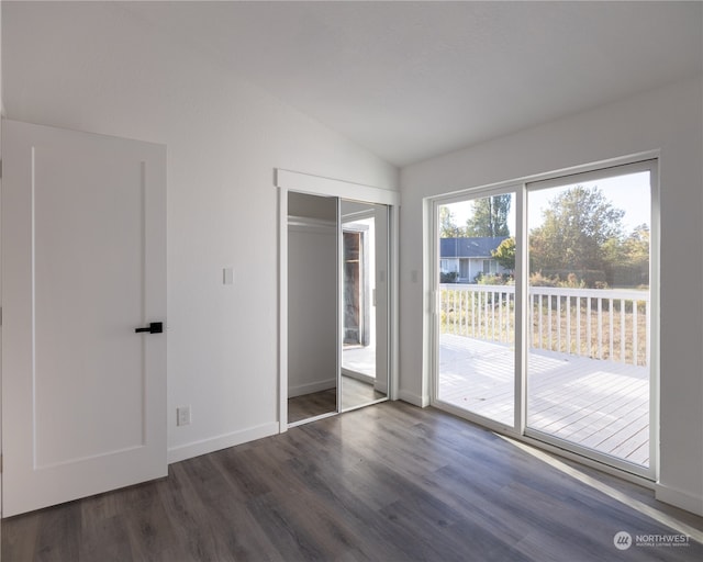 unfurnished bedroom featuring access to exterior, lofted ceiling, dark wood-type flooring, and a closet