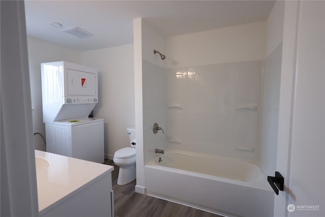 full bathroom with vanity, wood-type flooring, bathtub / shower combination, stacked washer and clothes dryer, and toilet