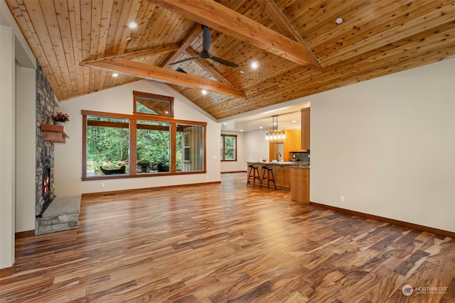 unfurnished living room with a stone fireplace, wooden ceiling, beamed ceiling, and wood-type flooring