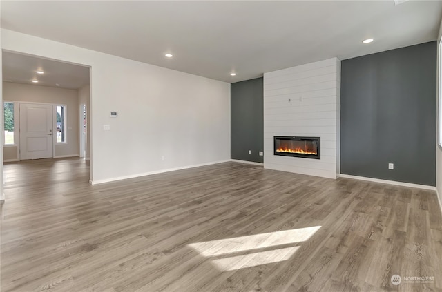 unfurnished living room featuring a large fireplace and light hardwood / wood-style floors