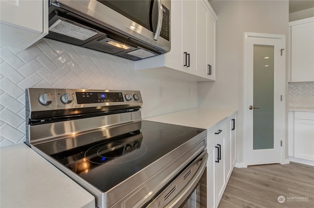 kitchen with stainless steel appliances, light hardwood / wood-style floors, and white cabinetry