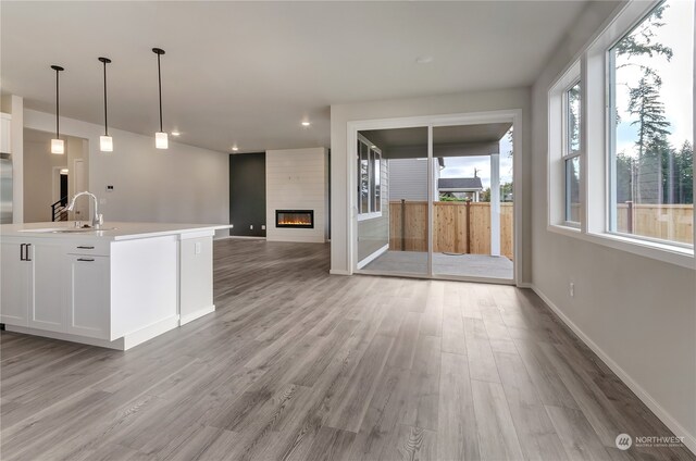 kitchen with hanging light fixtures, a fireplace, white cabinetry, and light hardwood / wood-style flooring