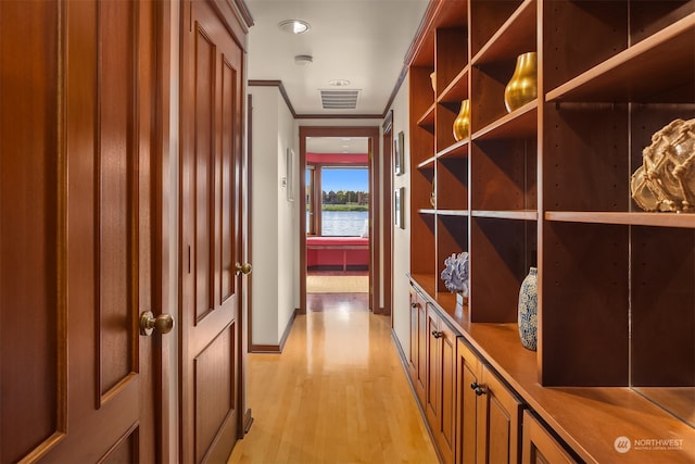 hallway with ornamental molding and light wood-type flooring