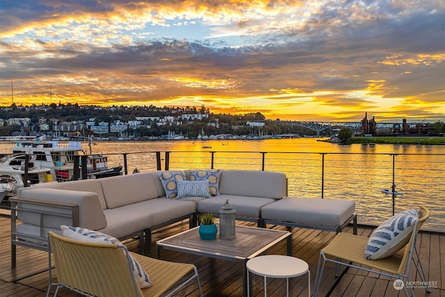 deck at dusk with an outdoor living space and a water view