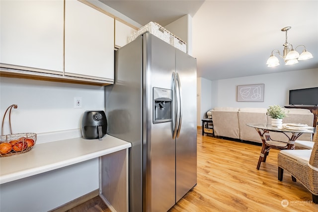 kitchen featuring pendant lighting, white cabinets, light hardwood / wood-style flooring, stainless steel fridge, and a chandelier