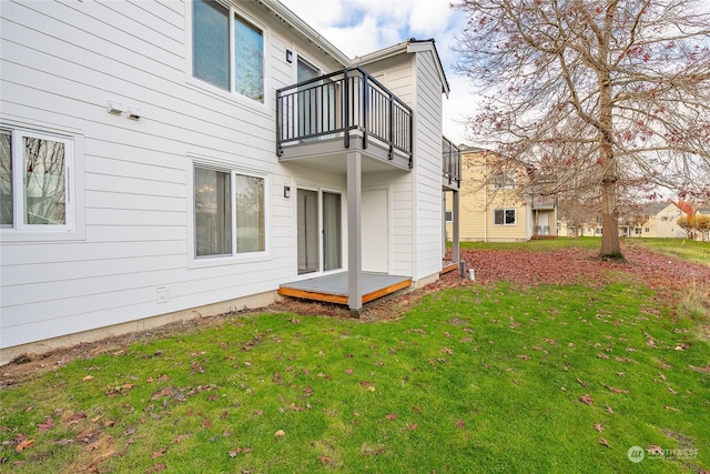 back of house featuring a lawn and a balcony