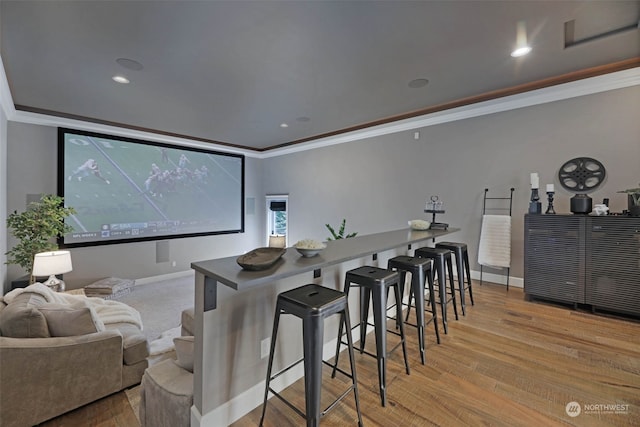 home theater room featuring crown molding and light hardwood / wood-style flooring