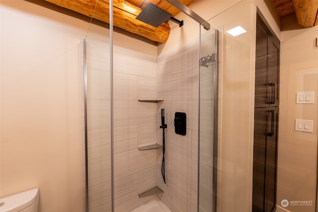 bathroom featuring a shower with shower door and toilet