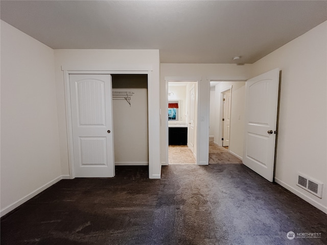 unfurnished bedroom with a closet and dark carpet