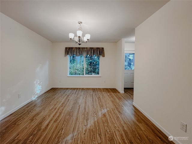 unfurnished dining area with light wood-type flooring and a notable chandelier