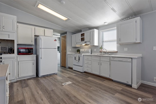 kitchen featuring visible vents, under cabinet range hood, vaulted ceiling, wood finished floors, and white appliances