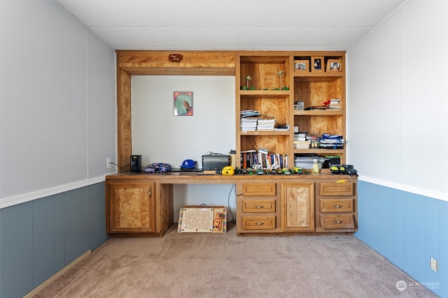 carpeted office featuring wood walls and built in desk