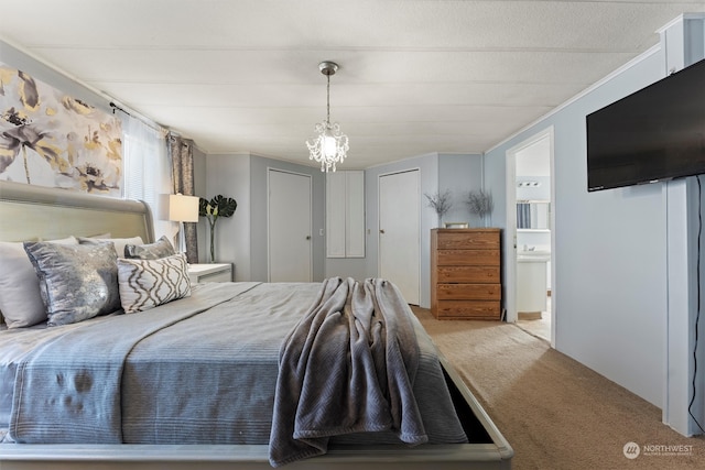 bedroom with light colored carpet, an inviting chandelier, and ensuite bath